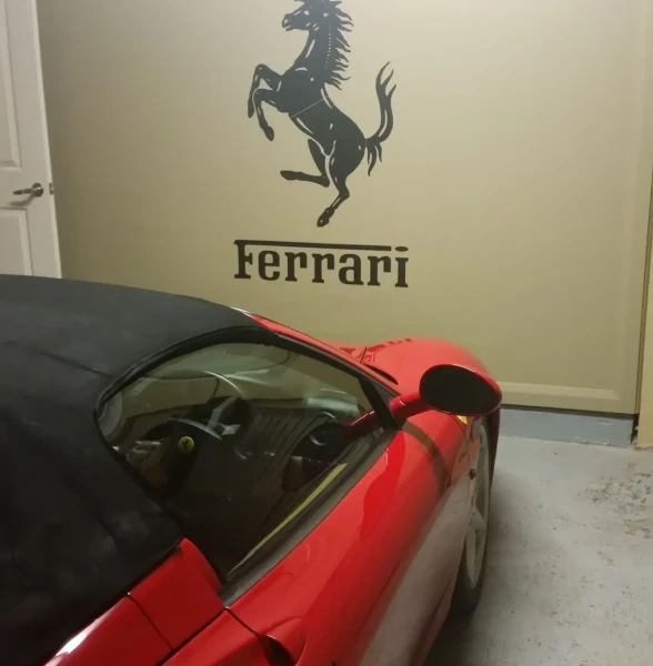 Red convertible in garage with Ferrari logo